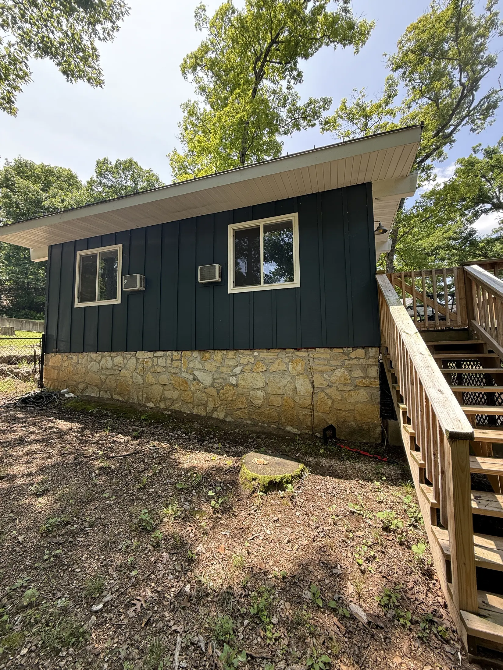 Dark-sided small home exterior with windows and steps.