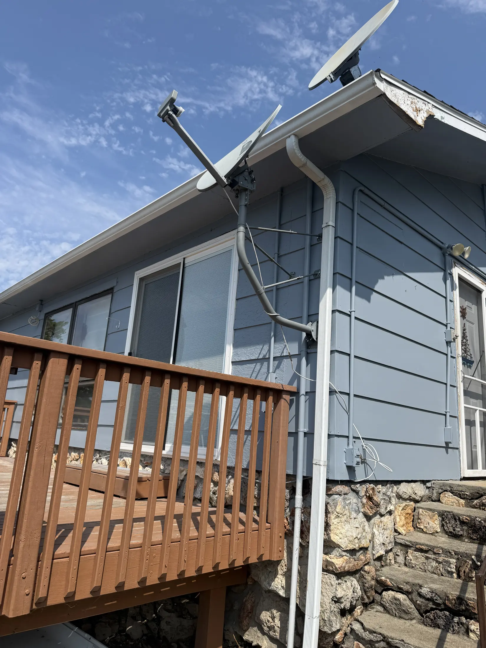 Gray-sided home exterior beside a wooden deck railing.