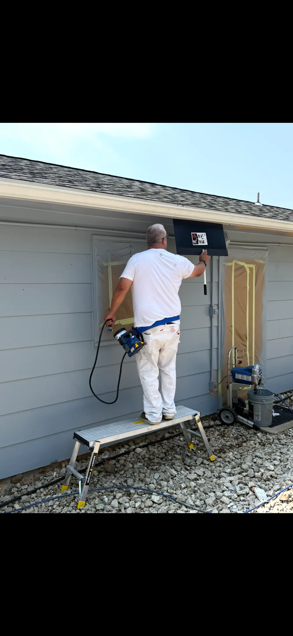 Person working beside an exterior garage wall.