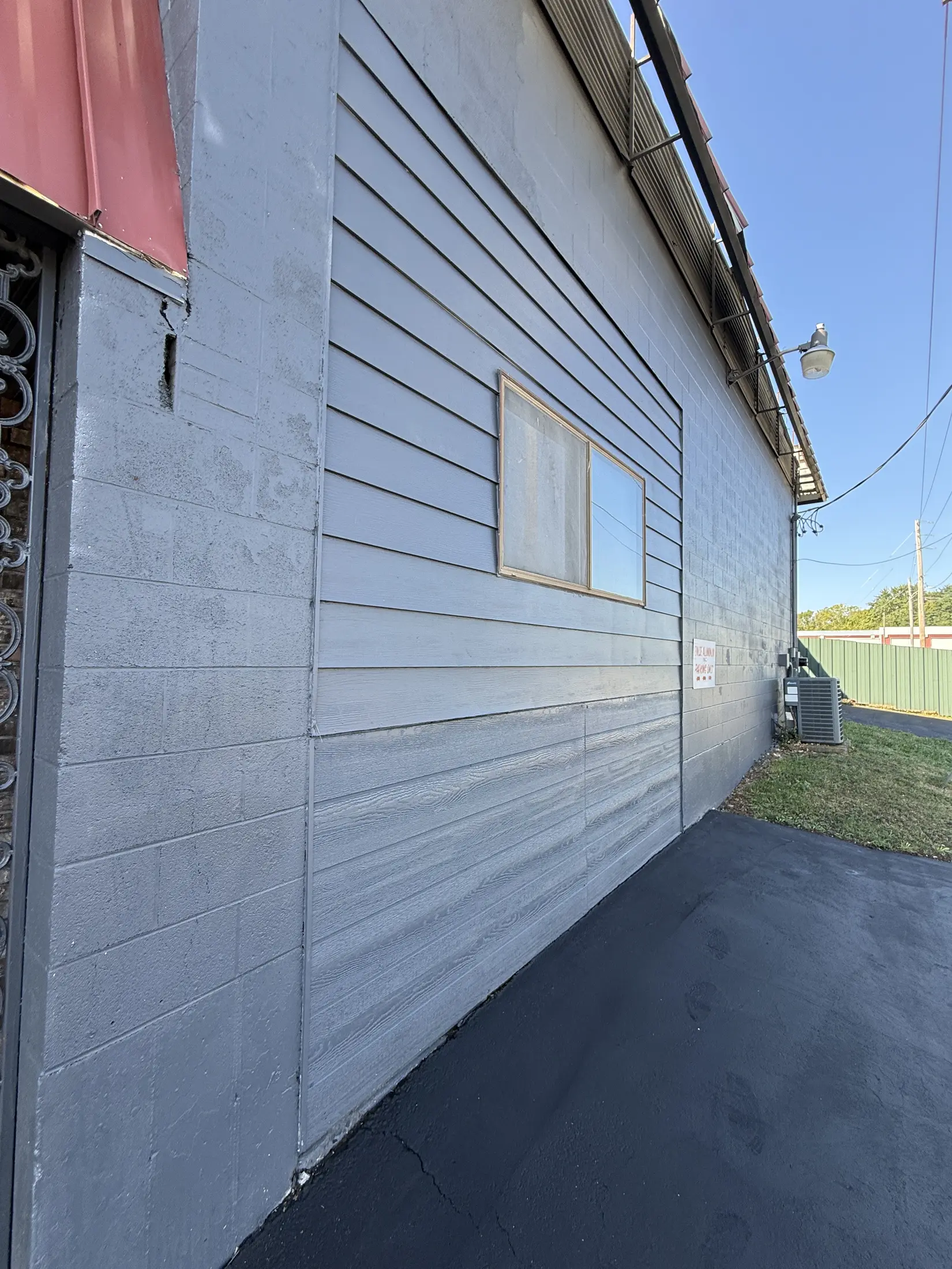 Gray painted exterior commercial wall with a small window.