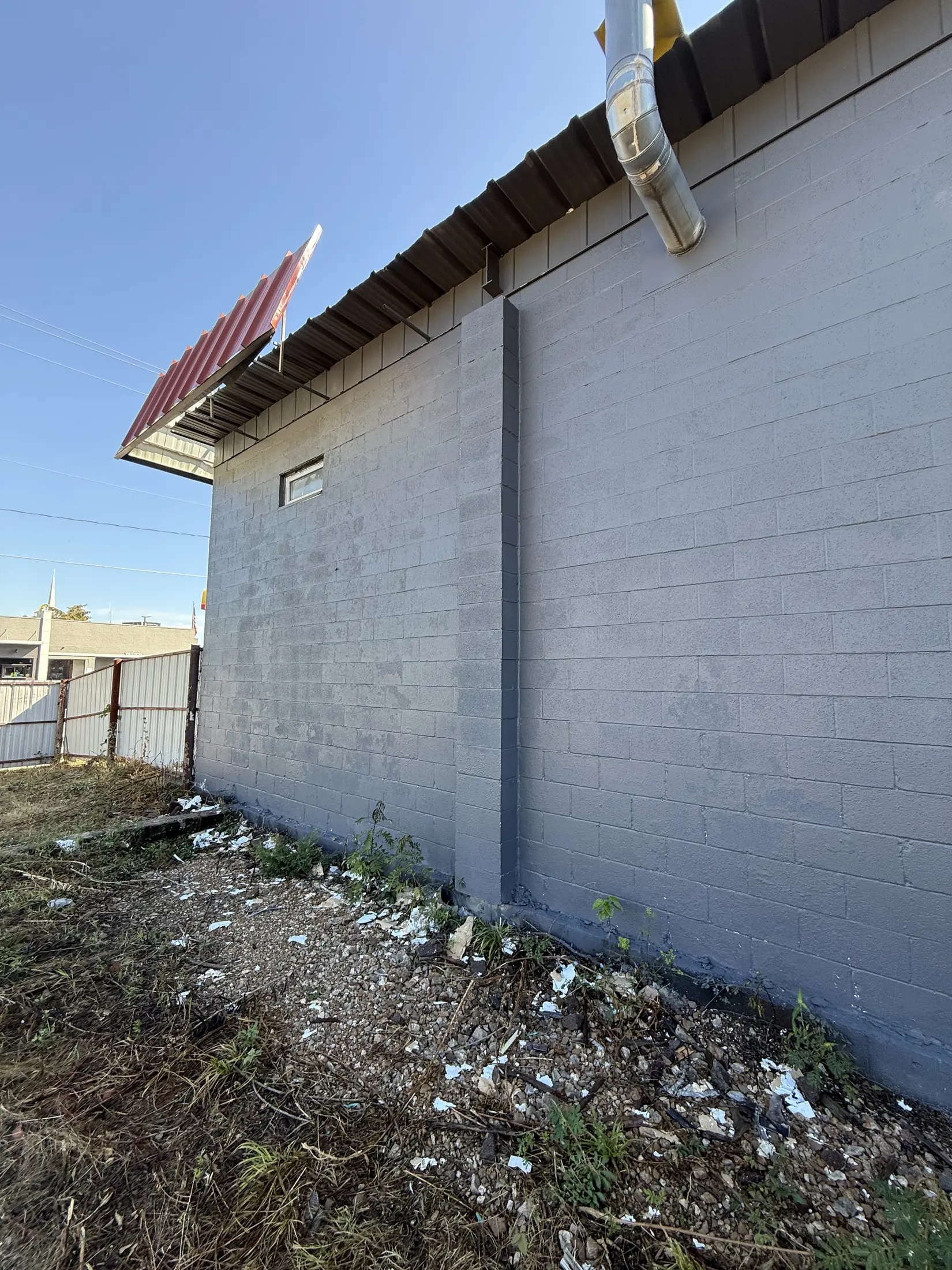 Gray painted exterior commercial wall beneath a red roof overhang.