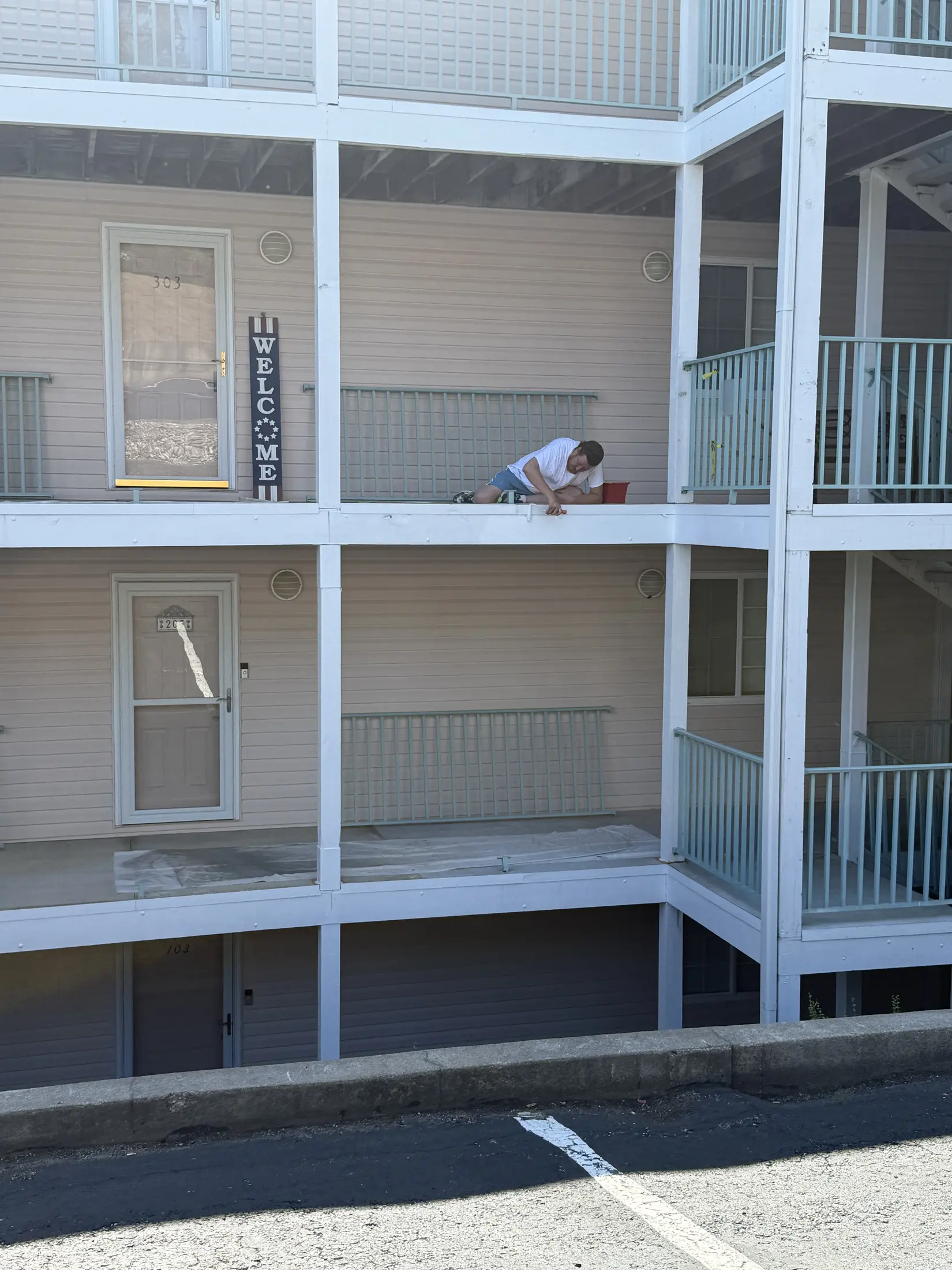 Worker standing on an upper-level balcony of a condominium exterior.