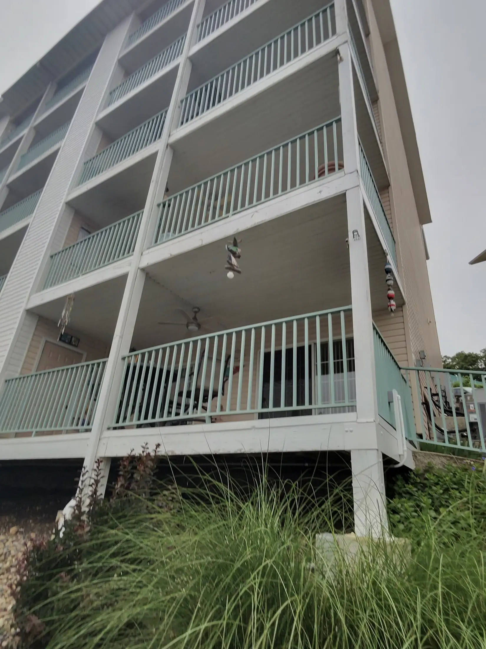 Multi-story condominium exterior with balconies and a white railing viewed from ground level.