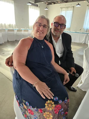 A woman and a man seated together at an indoor event space.